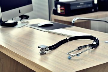 Scrivania sulla quale c'è un computer e uno stetoscopio. 