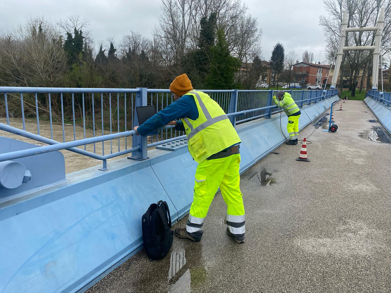 Tecnici in giubbotto alta visibilità sul ponte blu all'opera per eseguire i rilievi.