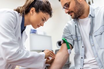 Fotografia di una dottoressa che esegue un prelievo di sangue a un signore.