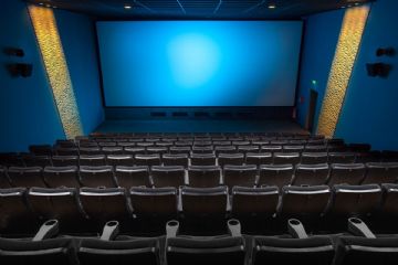 sala cinematografica con schermo illuminato e poltrone in primo piano
