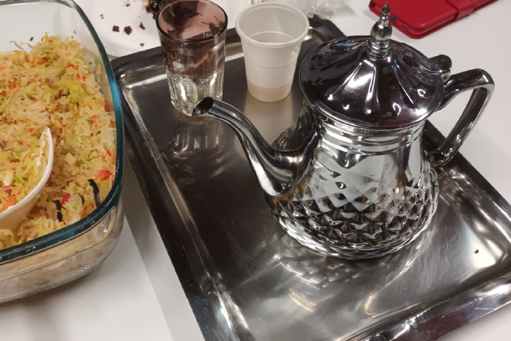 Bricco da tè mediorientale con accanto vassoio di cous cous e bicchieri per il servizio. L'immagine raffigura il momento di convivialità che si è svolto per celebrare la fine del corso. 