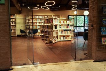 una sezione della biblioteca con scansie di libri, luci circolari e porta d'ingresso