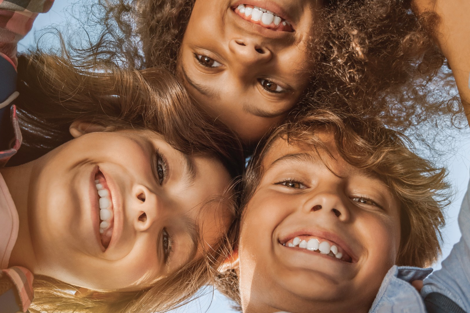 Bambine e bambiini sorridenti in primo piano fotografati dal basso.